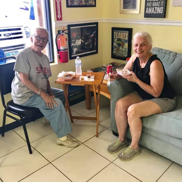 Two smiling customers enjoying Colombian food and drinks at Empanada Brothers restaurant.