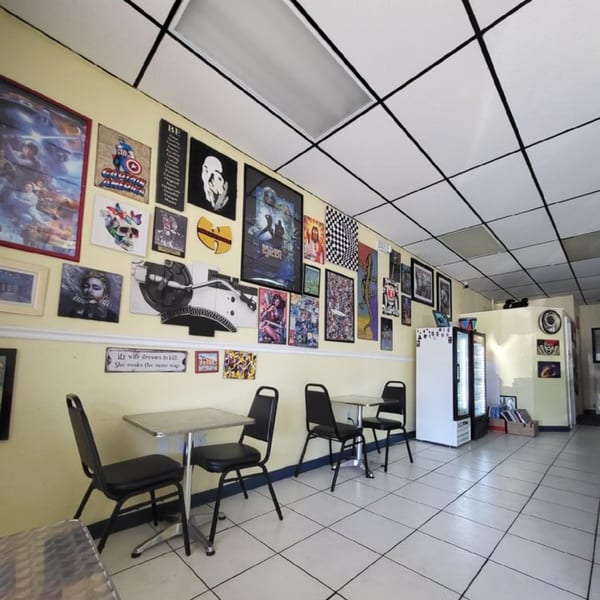 Interior of Empanada Brothers with yellow walls, pop culture art, black tables, and chairs.