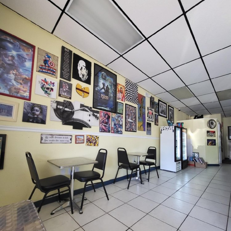 Interior of Empanada Brothers with yellow walls, pop culture art, black tables, and chairs.