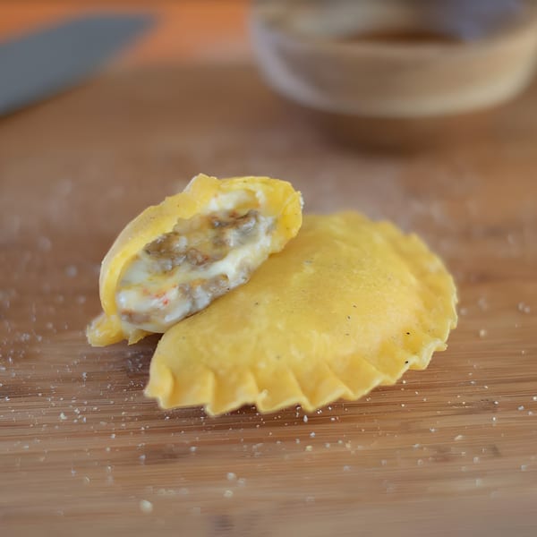 A Colombian empanada, cut open to reveal a creamy, meaty filling, on a wooden board.