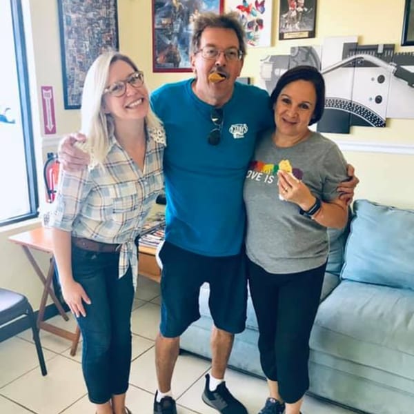 Three people, two women and one man, posing happily inside Empanada Brothers restaurant.