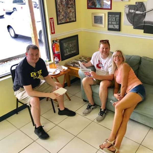 Three happy customers, two men and one woman, relaxing in the Empanada Brothers dining area.