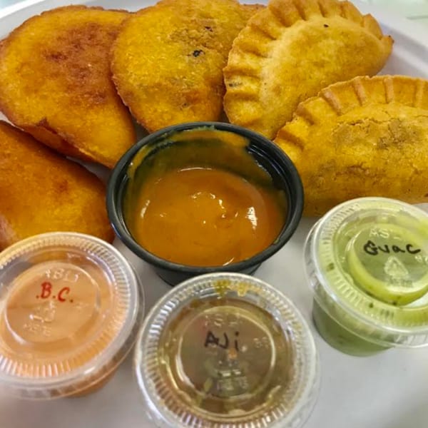Golden Colombian empanadas with various dipping sauces, including aji and guacamole.