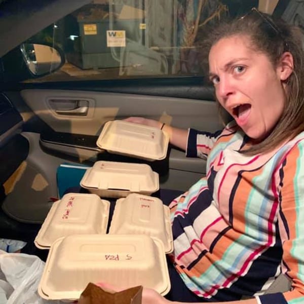 Woman in a car with a surprised expression, surrounded by multiple Empanada Brothers takeout containers.