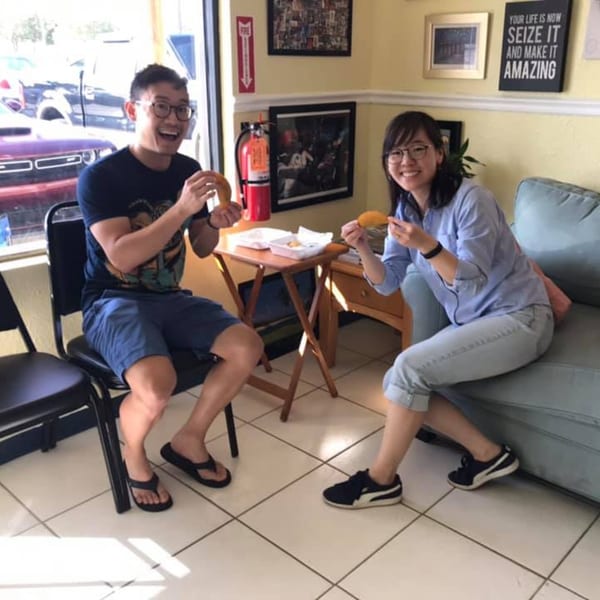 Two happy customers enjoying Empanada Brothers' Colombian empanadas inside the restaurant.