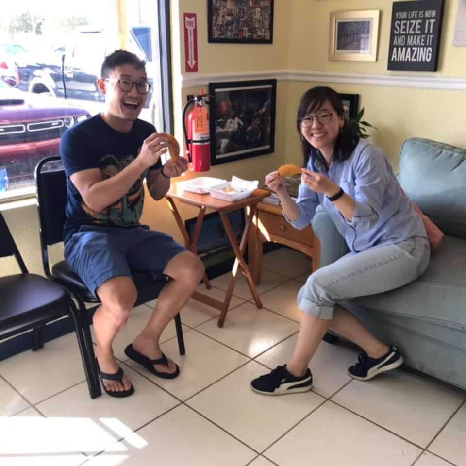 Two happy customers enjoying Empanada Brothers' Colombian empanadas inside the restaurant.